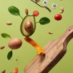 A creative arrangement of paleo diet ingredients floating above a wooden board on a green background.